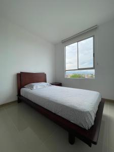 a white bedroom with a bed and a window at Apartamento sur de cali in Cali
