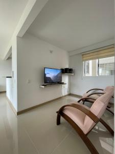 a living room with two chairs and a flat screen tv at Apartamento sur de cali in Cali