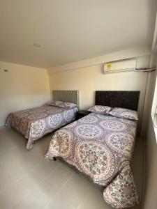two beds in a small room with at HOTEL HOME UNICENTRO in Villavicencio