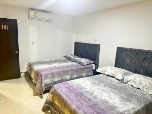2 camas en una habitación con mantas moradas en HOTEL HOME UNICENTRO, en Villavicencio