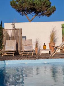 twee stoelen en een tafel naast een zwembad bij Casa Atlântico Carvalhal Comporta, apartamento piscina aquecida in Carvalhal