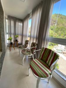 ein Wohnzimmer mit Stühlen und einem großen Fenster in der Unterkunft Apartamento completo no centro de Domingos Martins in Domingos Martins