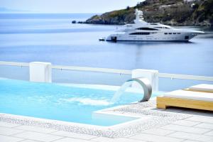 a yacht in the water with a cruise ship at Nissaki Boutique Hotel in Platis Yialos Mykonos