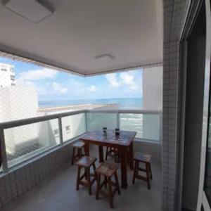 einen Tisch und Stühle auf einem Balkon mit Meerblick in der Unterkunft Apartamento Vista Mar Mongaguá in Mongaguá