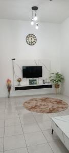 - un salon blanc avec une horloge et un tapis dans l'établissement QM_Homestay Bagan Serai, à Bagan Serai