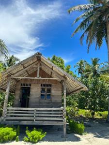 een klein huis aan het strand met een palmboom bij Palambak Paradise Resort Pulau Banyak in Pulau Palambakbesar