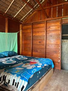 uma cama num quarto com paredes de madeira em Palambak Paradise Resort Pulau Banyak em Pulau Palambakbesar