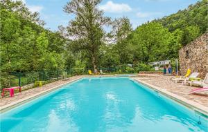 a swimming pool with blue water and chairs and trees at 2 Bedroom Stunning stacaravan In Conques-en-rouergue in Conques-en-Rouergue