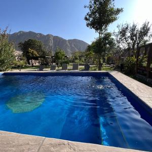 a swimming pool with blue water and mountains in the background at Refugio de Santiago Ecolodge in Lunahuaná