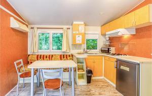 eine kleine Küche mit einem Tisch, Stühlen und einer Theke in der Unterkunft Nice stacaravan In Conques En Rouergues With Kitchen in Conques-en-Rouergue