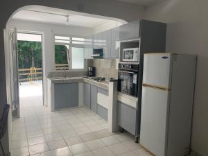 a kitchen with a white refrigerator and a sink at Les Roses Porcelaines in Sainte-Rose