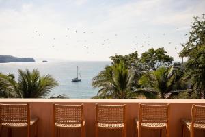 a balcony with chairs and a sailboat in the water at Casa Liquen in Chacala