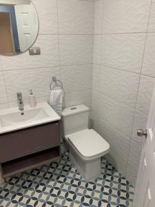 a bathroom with a white toilet and a sink at departamento leon gallo (e) in Temuco