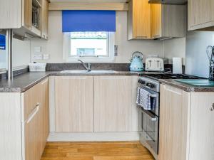 a kitchen with wooden cabinets and a stove top oven at Merse Place 4 - Uk45159 in Mainsriddle