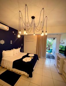 a bedroom with a large bed and a chandelier at Charme do Dido in Ilha de Boipeba