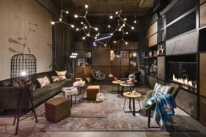 un soggiorno con divano e alcuni tavoli e sedie di Moxy Dresden Neustadt a Dresda