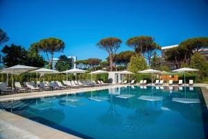 a large swimming pool with chairs and umbrellas at Holiday Inn Rome - Eur Parco Dei Medici by IHG in Rome