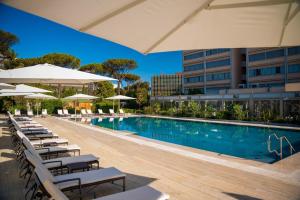 una piscina con sedie e ombrelloni accanto a un edificio di Holiday Inn Rome - Eur Parco Dei Medici, an IHG Hotel a Roma