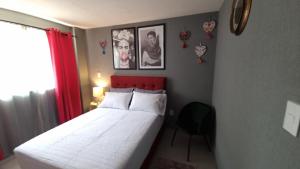1 dormitorio con cama blanca y cabecero rojo en Departamento Nuevo a 4 minutos del Aeropuerto, en Ciudad de México