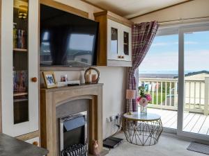 a living room with a fireplace and a tv at Sea View 14 - Uk45161 in Mainsriddle