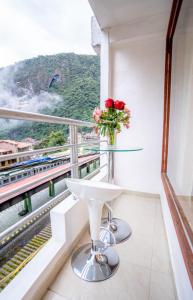 una mesa con un jarrón de flores en el balcón en Vista Machu Picchu, en Machu Picchu