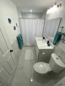 a white bathroom with a toilet and a sink at Mango Tree House in Lake Worth