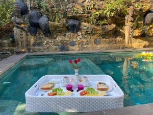 a table with food on it next to a swimming pool at Sari Mimpi Kutuh in Ubud