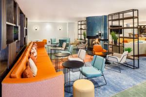 a lobby with orange furniture and tables and chairs at Delta Hotels by Marriott Warwick in Warwick