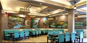 SīkarHotel Annpurna Regency的一间设有蓝色桌椅和壁画的餐厅