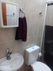ein Badezimmer mit einem WC, einem Waschbecken und einem Spiegel in der Unterkunft 1 Casa piso superior e 1 Kitnet Térrea, individuais, o estacionamento área comum in Bertioga