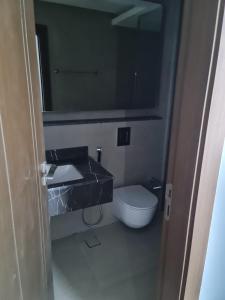 a bathroom with a toilet and a sink and a mirror at شقة مفروشة جديدة مؤثثة بالكامل بالجفير in Manama