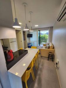 eine Küche und ein Wohnzimmer mit einem langen Tisch und gelben Stühlen in der Unterkunft Apartamento Beach Class Muro Alto in Porto De Galinhas