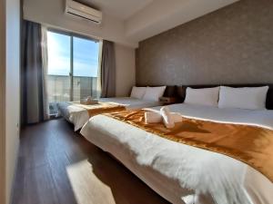 two beds in a hotel room with a large window at Ostay Vermillion Namba in Osaka