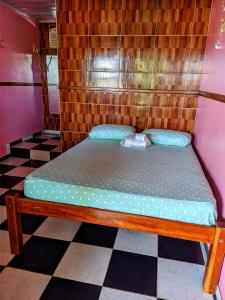 Cama de madera en habitación con suelo a cuadros en Pousada Aguiar en Rio Preto Da Eva