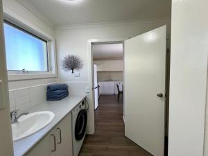 a white bathroom with a sink and a window at Gowings of Mallacoota in Mallacoota