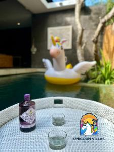 a bottle of gin sitting on a table next to a pool at Villa di Sawah - by Unicorn Villas Bali in Kerobokan