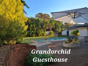 Un patio trasero con una fuente y una sombrilla. en The Grand Orchid Guesthouse, en Durban