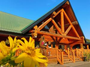a log cabin with a bear on the front porch at Bear's Claw Lodge in Cache Creek