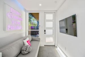 Sala de estar blanca con sofá gris y almohada rosa en Blueberry Container @ EADO Juice Box, en Houston