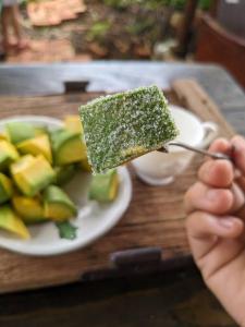 a person holding a piece of cake on a plate of fruit at Ivy Coffee Farm - Garden House in Ðưc Trọng