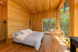 ein Schlafzimmer mit einem Bett in einem Holzzimmer mit einem Tisch in der Unterkunft Tanières MicroChalets Charlevoix in Baie-Saint-Paul