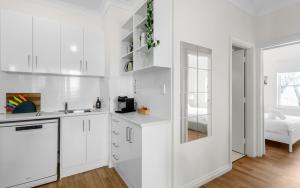 a white kitchen with white cabinets and a sink at SEA BREEZE @ Smugglers Inn in Victor Harbor