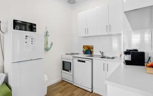 a white kitchen with white cabinets and appliances at SEA BREEZE @ Smugglers Inn in Victor Harbor