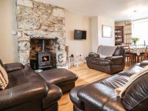 a living room with leather furniture and a stone fireplace at Artro View in Llanbedr