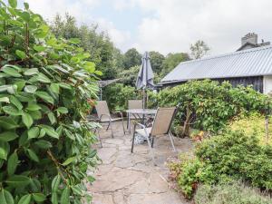 un patio con sillas, una mesa y una sombrilla en Artro View, en Llanbedr