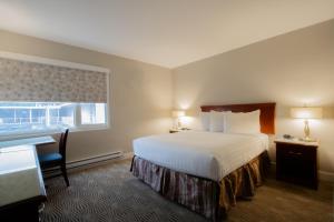 a hotel room with a bed and a desk and a window at Scott's Inn & Suites in Kamloops