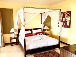 a bedroom with a canopy bed with white shoes on it at Cinnamon Beach Villas in Lamai