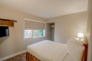 a bedroom with a white bed and a window at Scott's Inn & Suites in Kamloops
