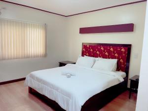 - une chambre avec un grand lit blanc et une tête de lit rouge dans l'établissement Jun and Helen Hotel and Restaurant, à Ángeles