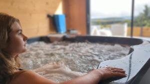 a young girl is in a hot tub at La flèche 1 de Super Besse - Chalet de Standing avec Jacuzzi privatif in Besse-et-Saint-Anastaise